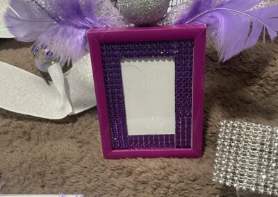 Purple decorative frame with feathers and glitter.